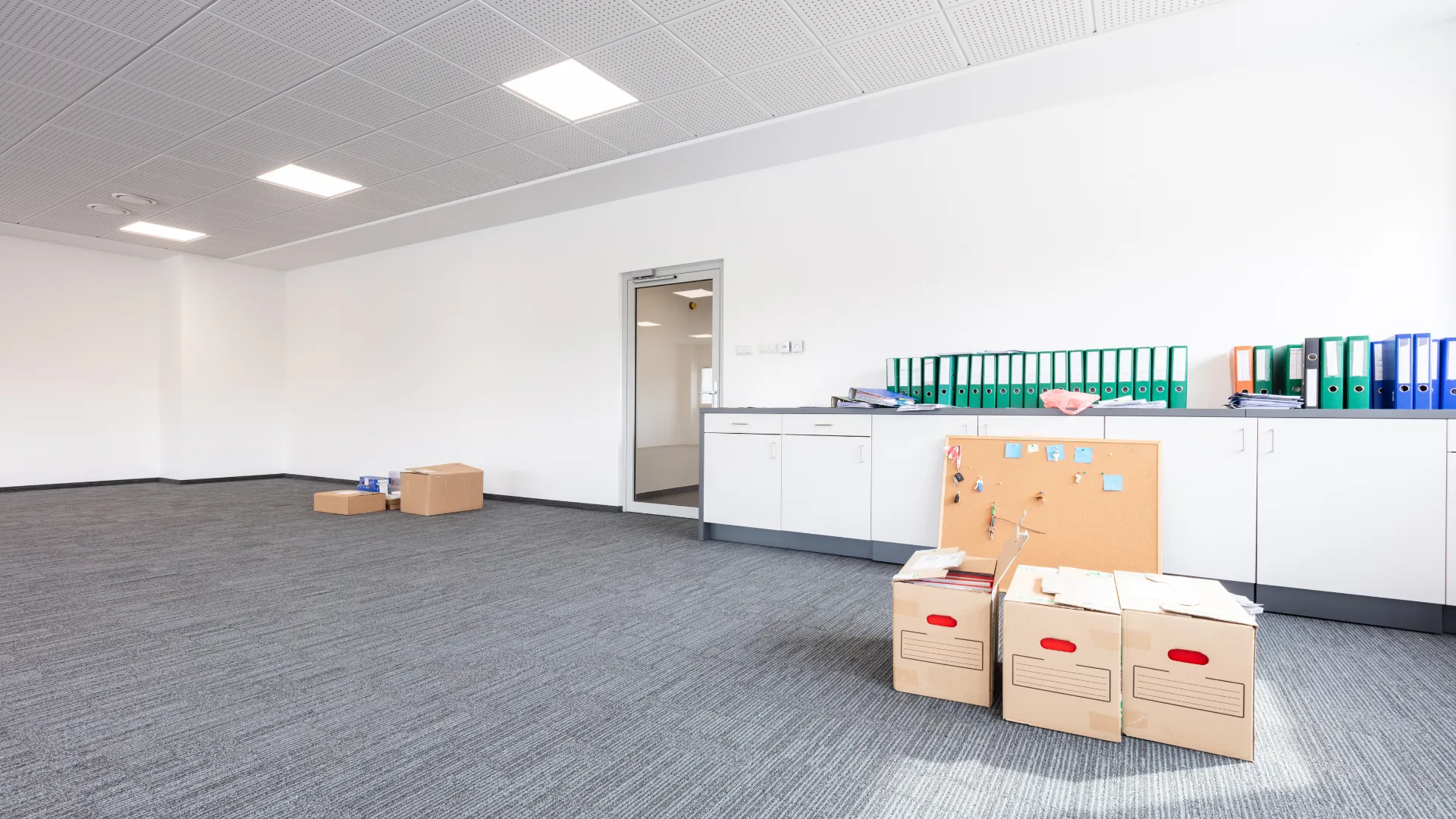 Office interior with rows of desks, computer monitors, and chairs.